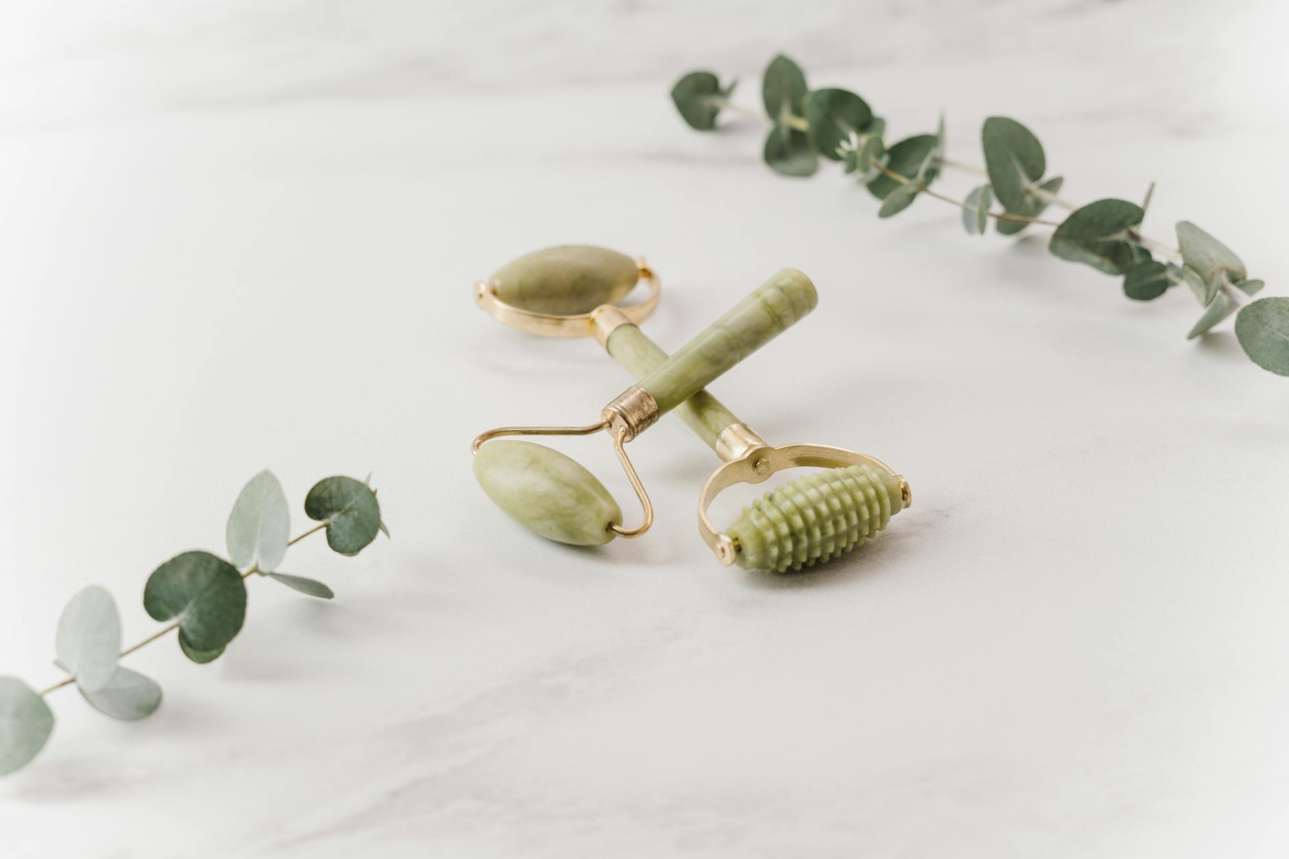 Jade facial roller on white spa towel with wellness treatment setup