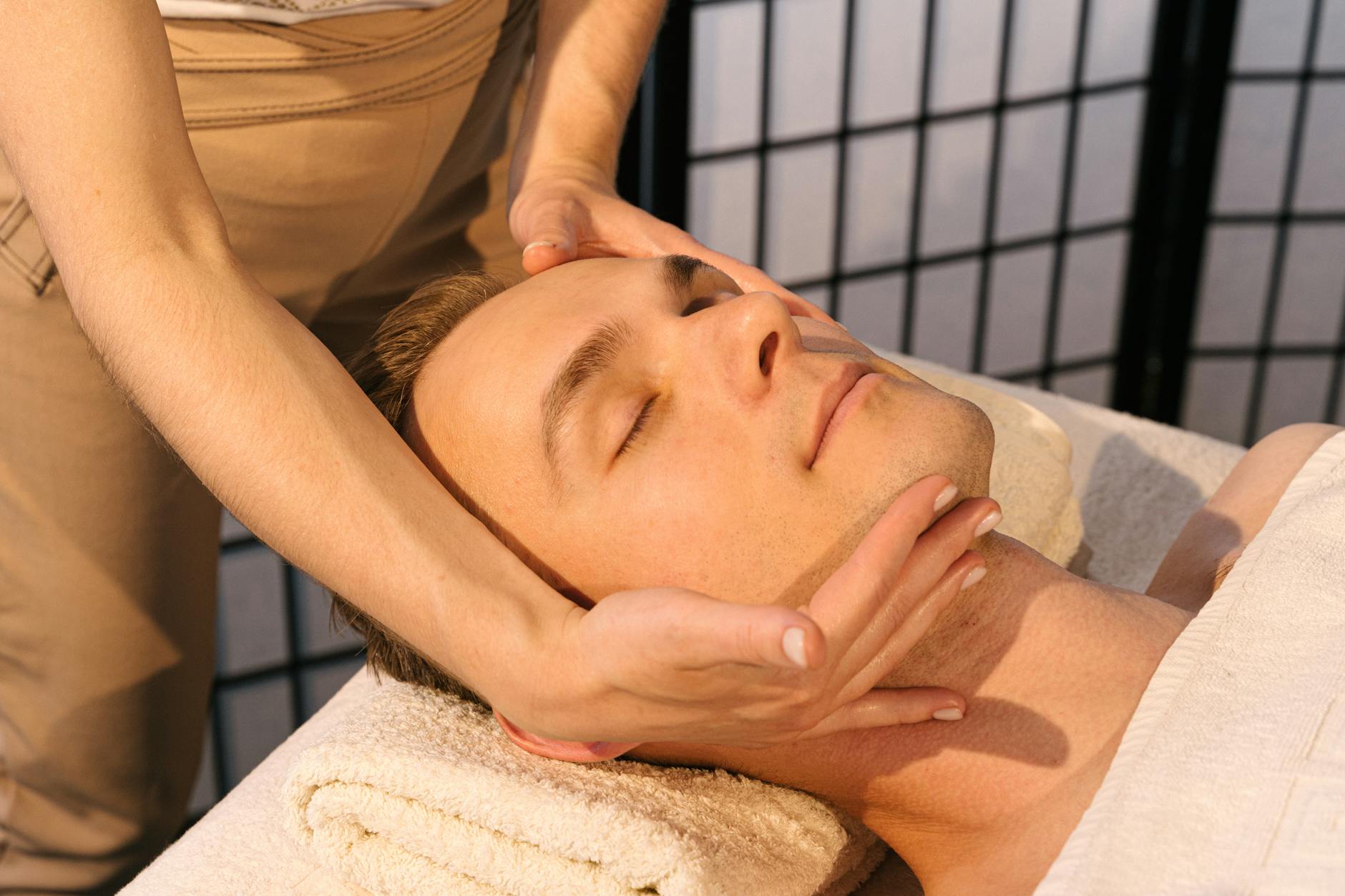 Professional massage therapist performing facial treatment on client in spa setting