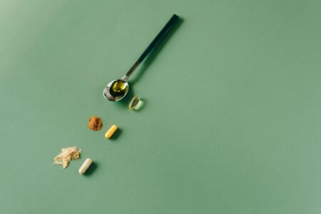 White collagen powder in measuring spoon with supplement jar in background