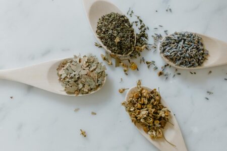 Various dried herbs and botanical ingredients arranged on a wooden surface for natural skincare preparation