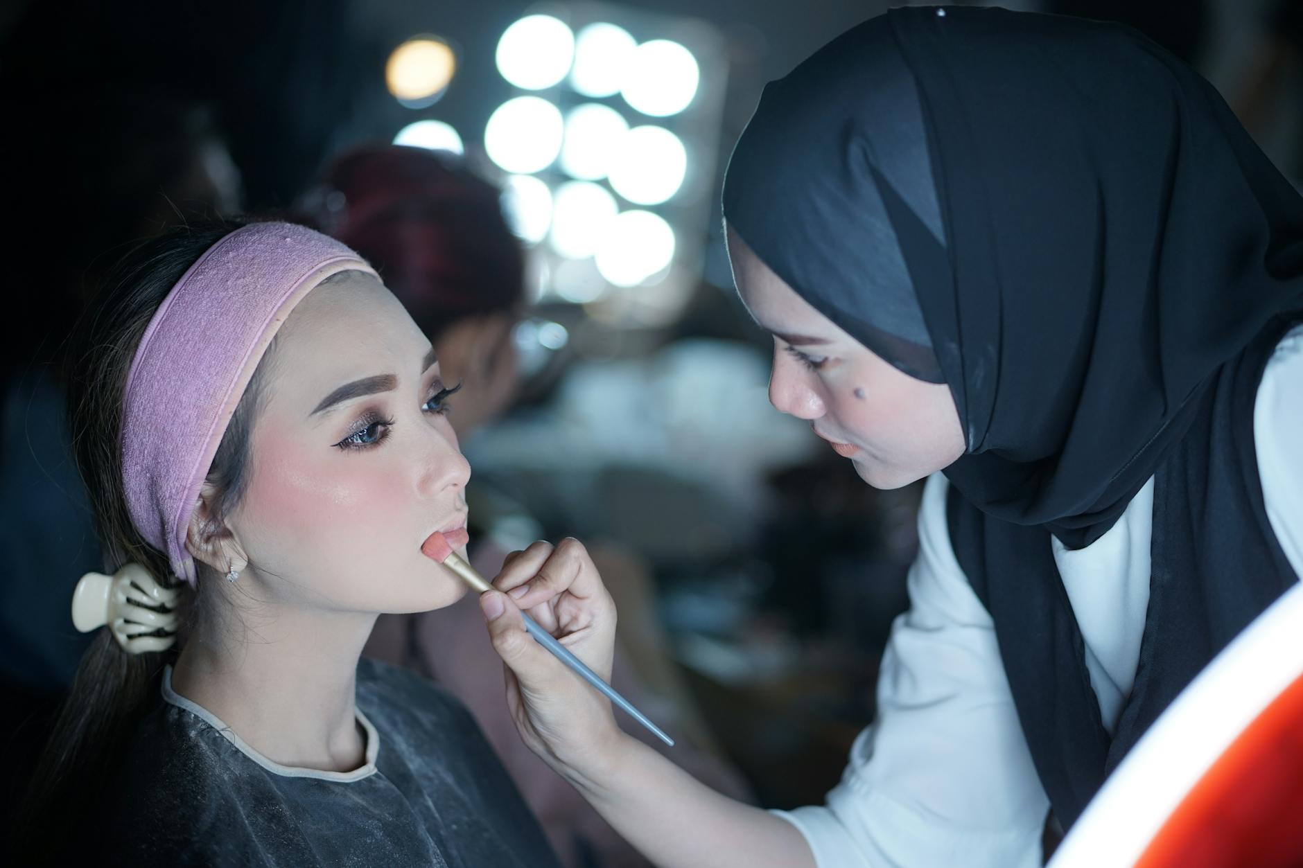 Professional makeup artist applying cosmetics to client in studio setting
