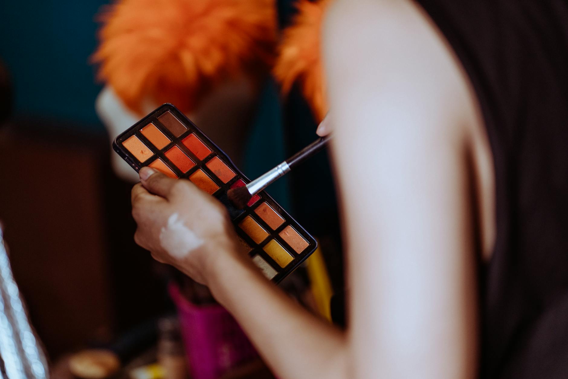 Professional makeup artist applying products to model's face in studio setting with professional lighting