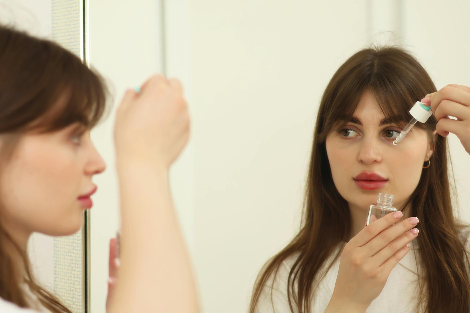 Woman applying facial serum as part of adapted glass skin routine