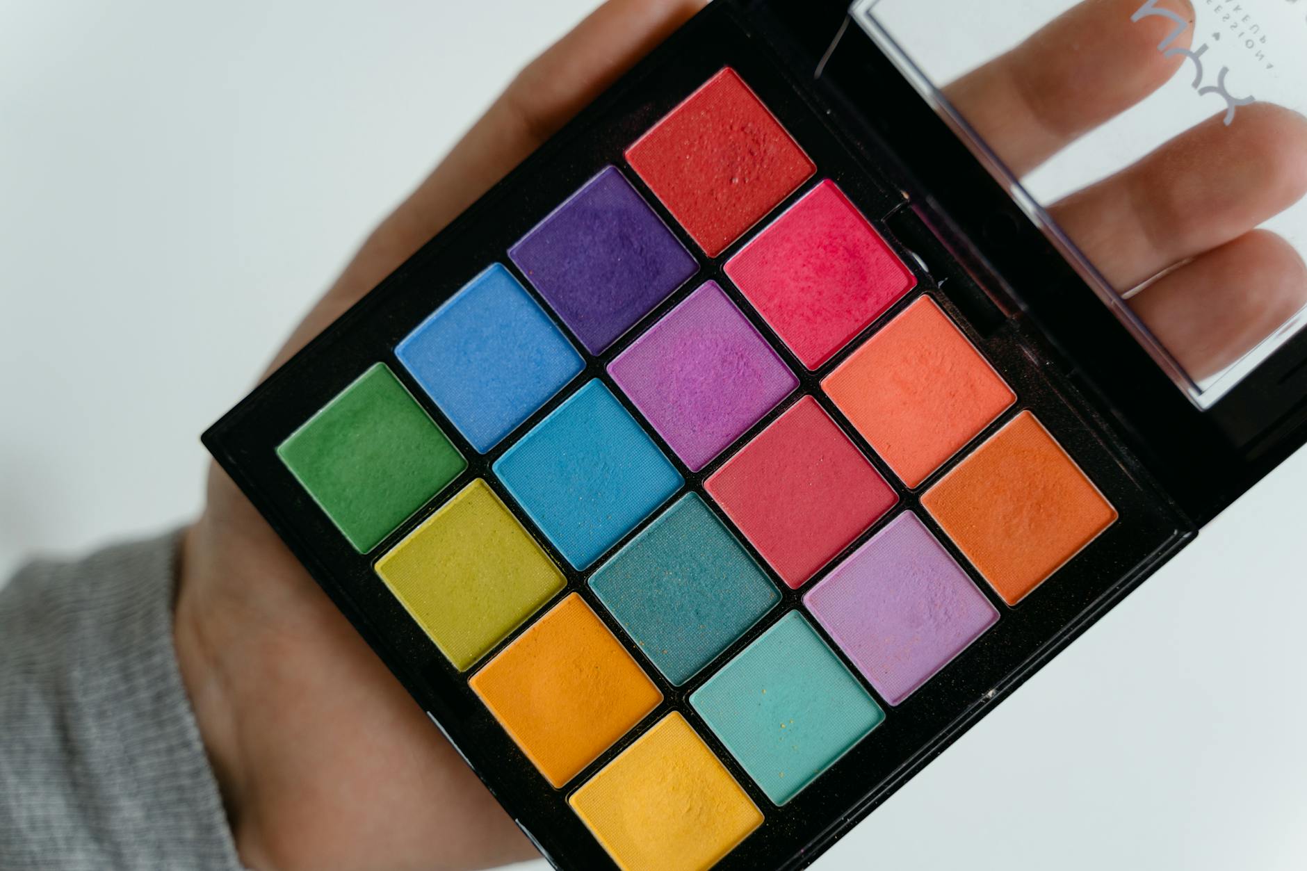 Vibrant makeup palettes with rainbow eyeshadows and bold lipsticks arranged on vanity