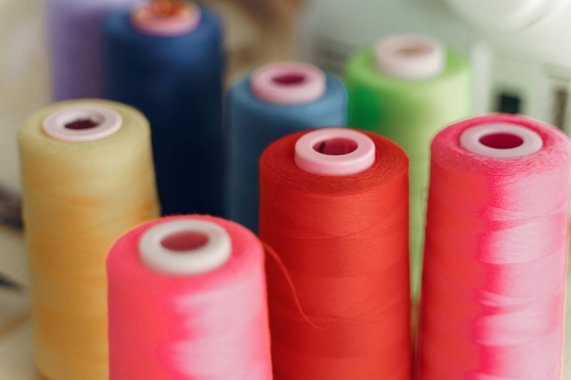 Colorful spools of thread and fabric samples arranged on a crafting table