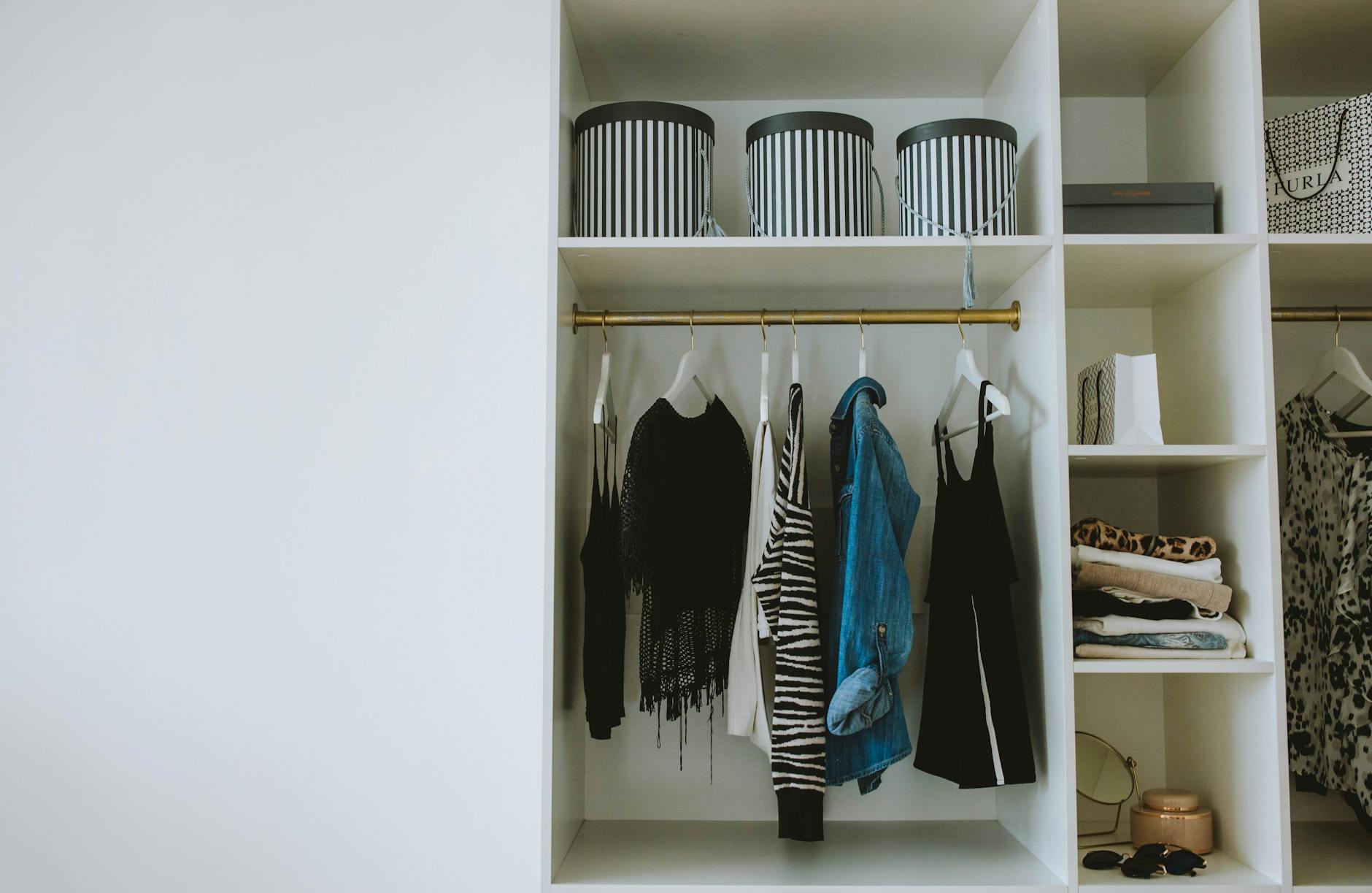 Neutral-toned professional clothing hanging in closet including blazers and cardigans