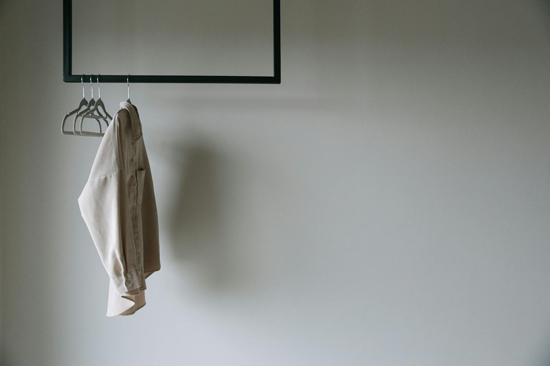 Minimalist wardrobe pieces in neutral tones hanging in organized closet