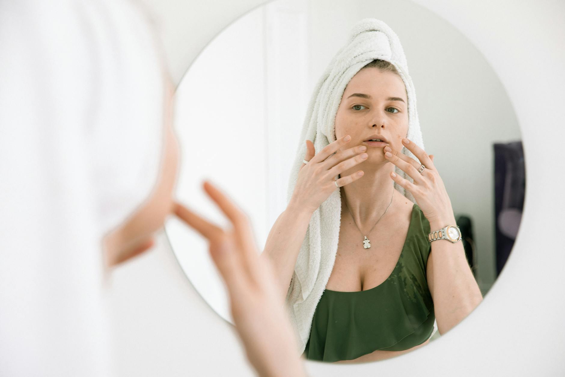 Person following skincare routine while looking in bathroom mirror with good lighting