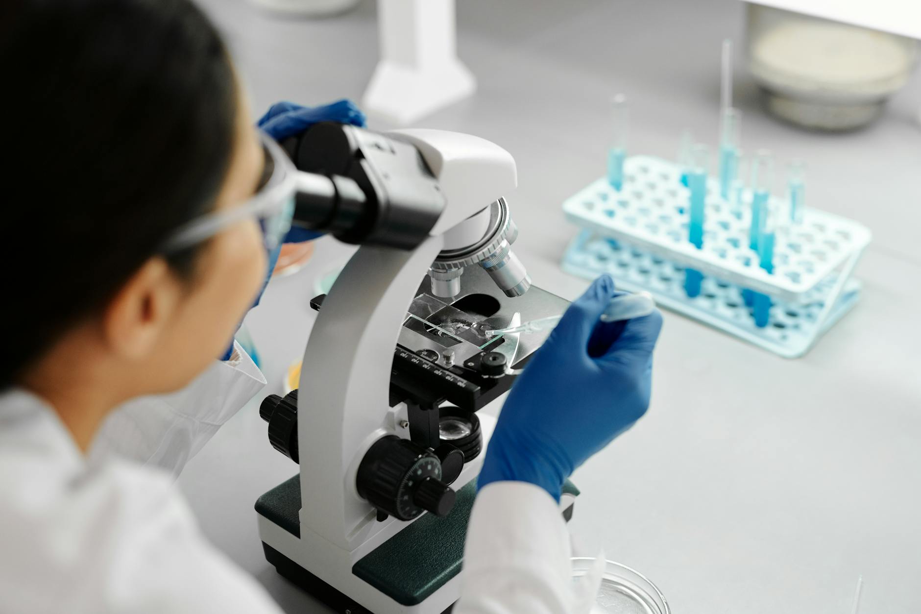 Scientist examining plant extracts in modern laboratory setting with microscope and testing equipment