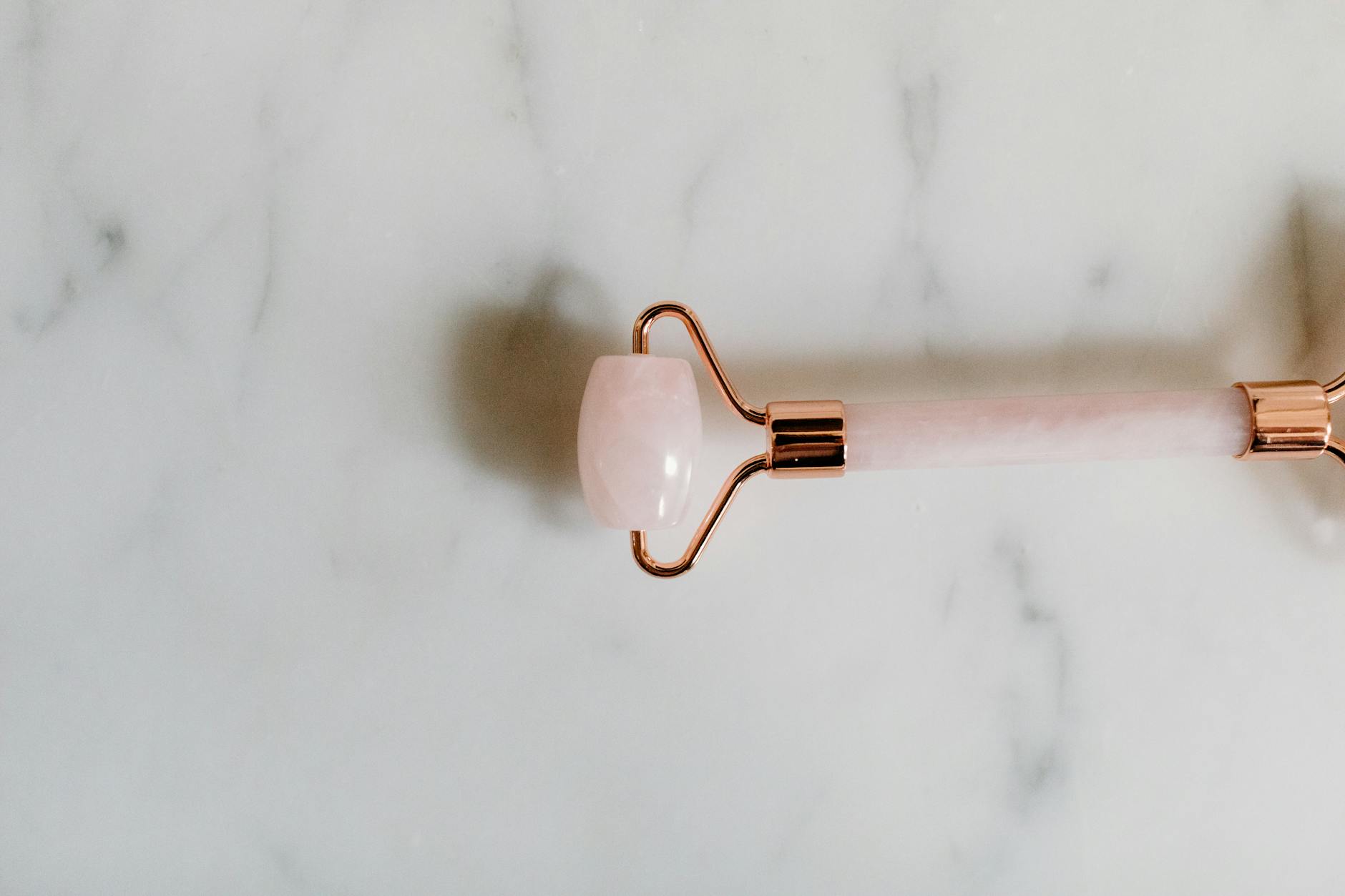 Collection of jade and rose quartz beauty tools arranged on marble surface for skincare routine