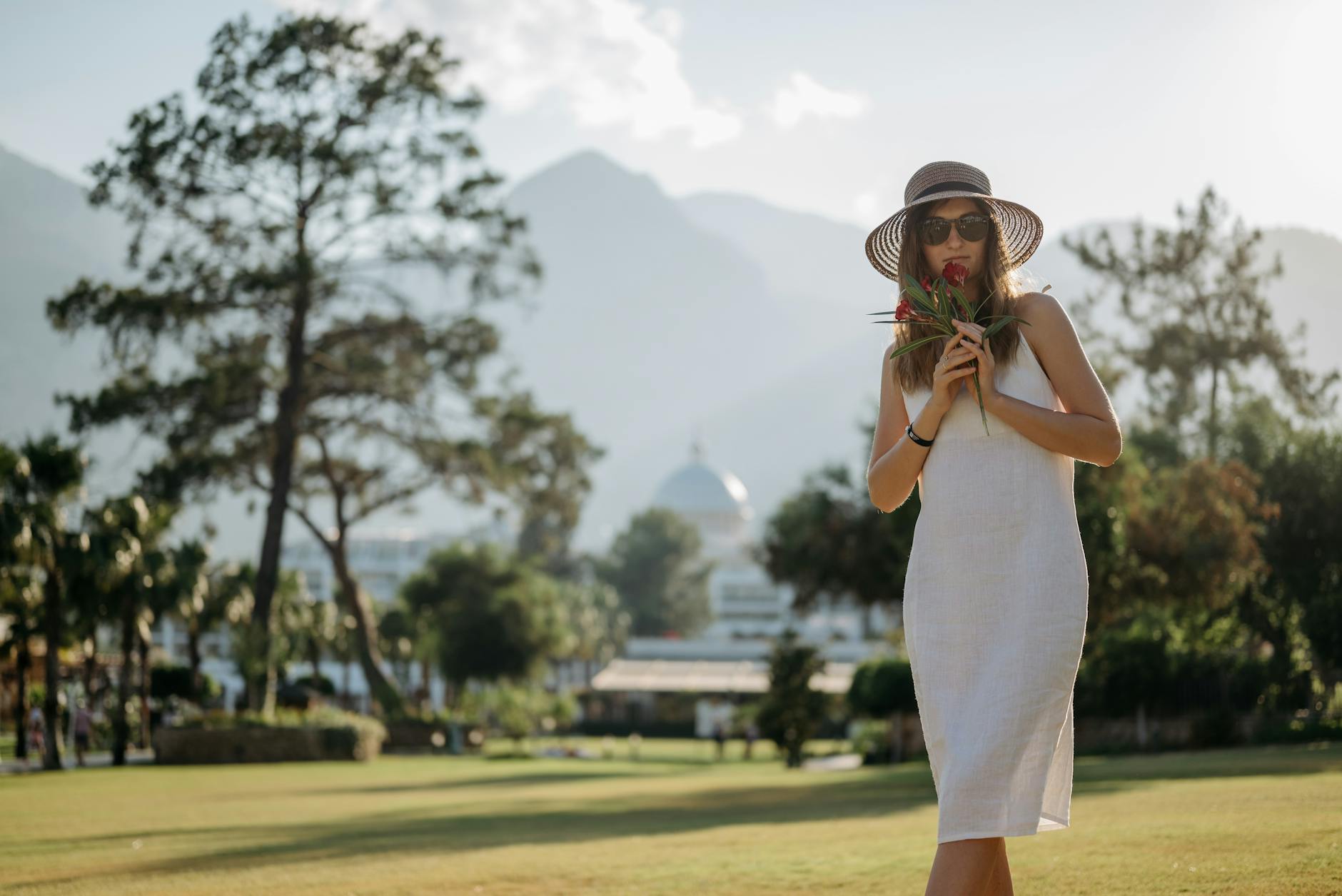Person wearing ivory linen trousers and a loose white shirt in a minimal summer setting