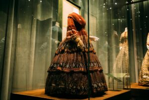Elegant vintage designer dress displayed at an upscale auction house with bidding paddles visible