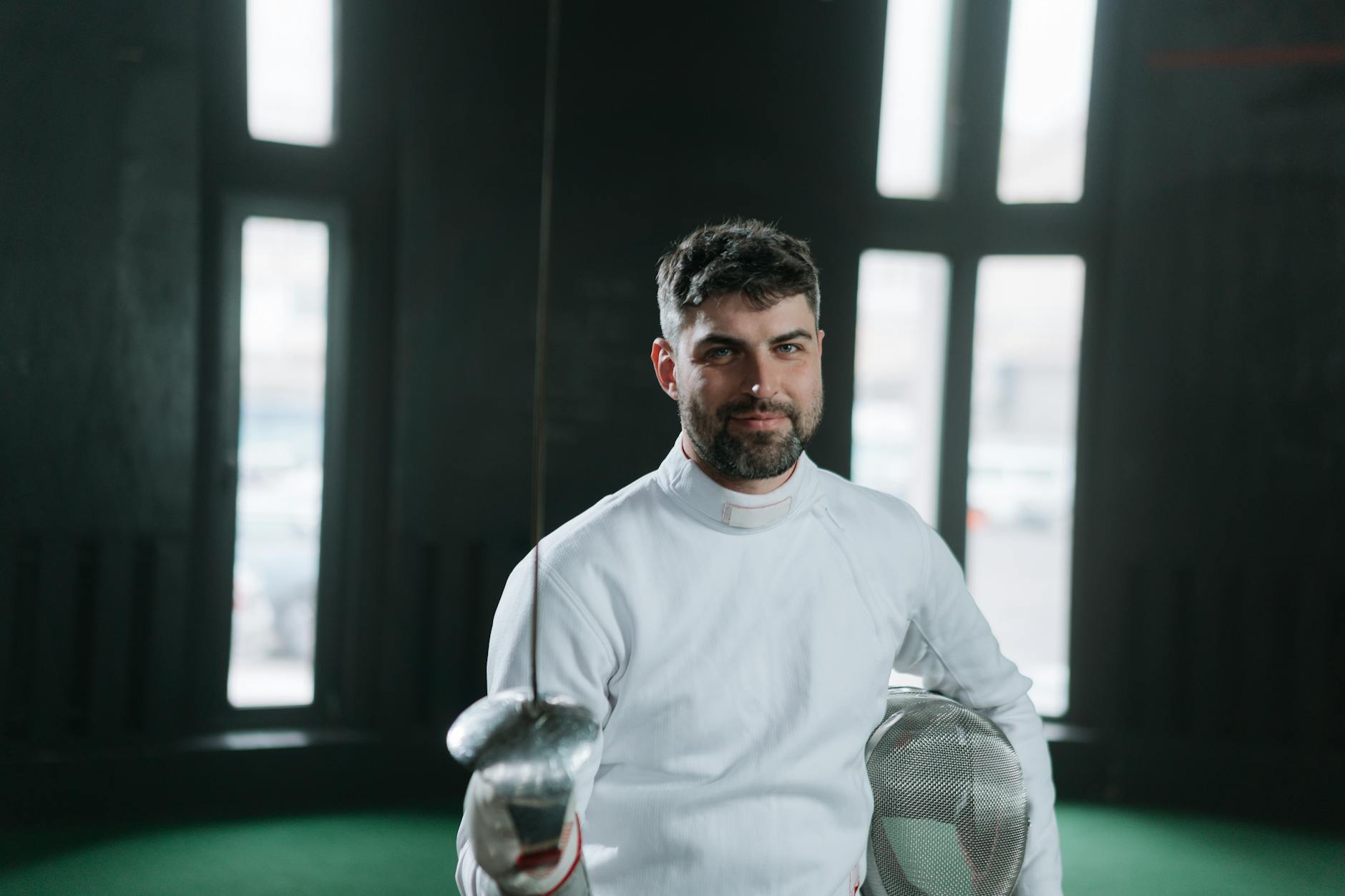Fencer in traditional white uniform showing the padded jacket silhouette and high collar