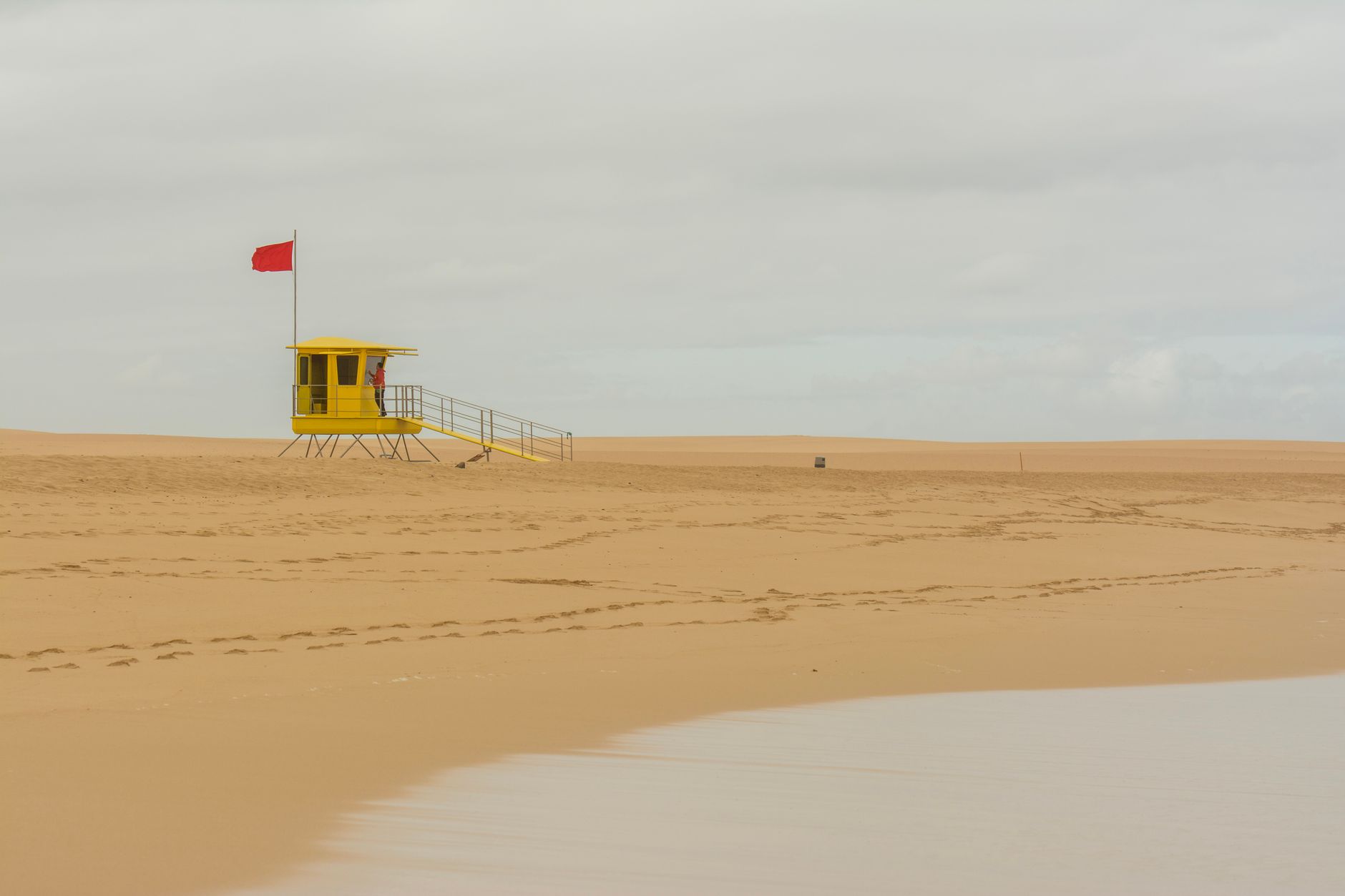 Brightly colored lifeguard tower on a sunny beach in bold orange and white