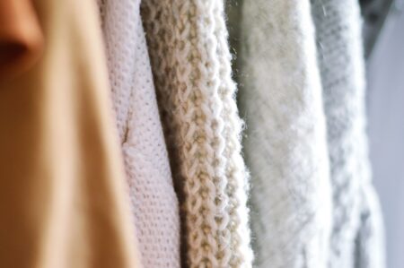Neatly folded polo wrap and quarter-zip knit layers in neutral tones arranged on a flat surface