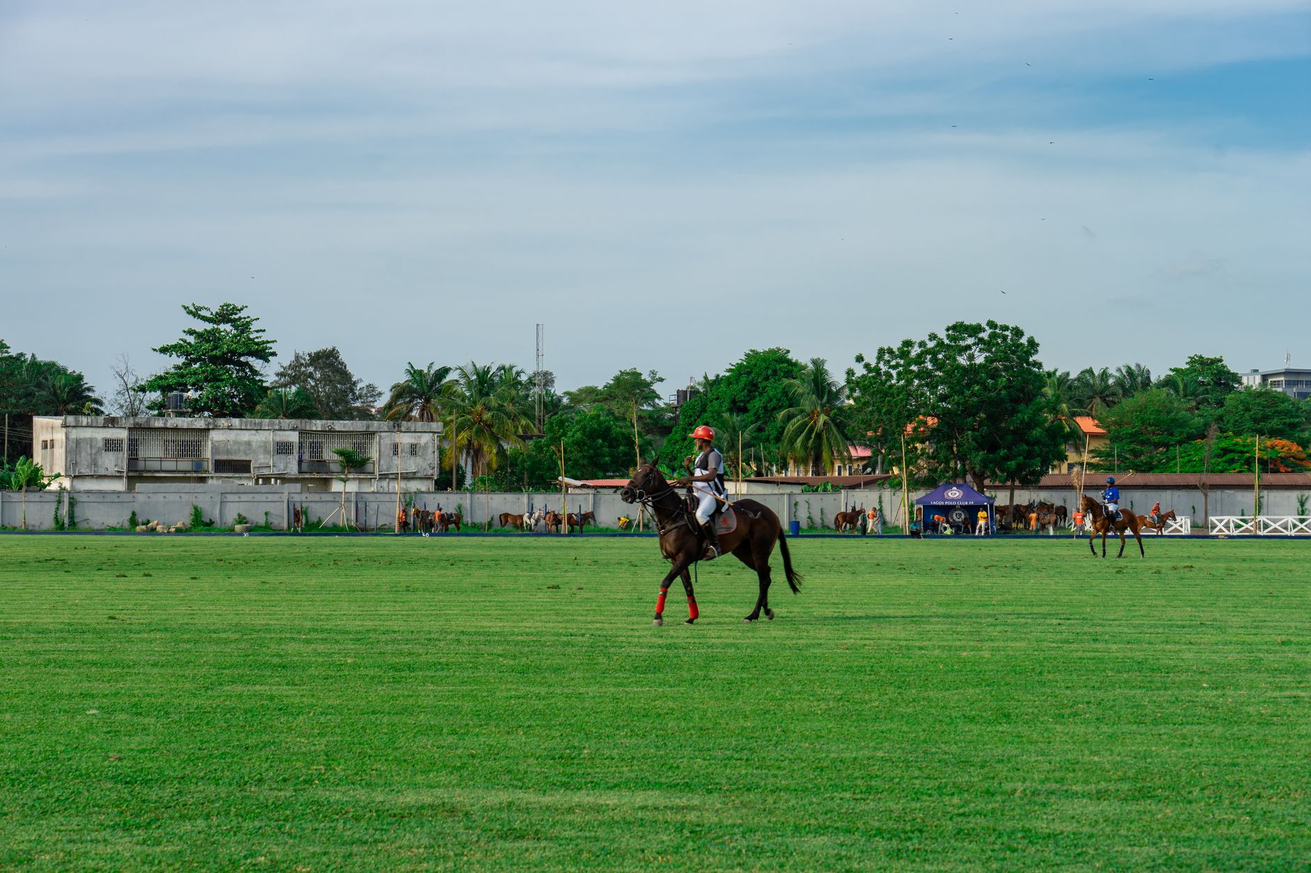 Polo players on horseback in bright team colours during a cross-country match