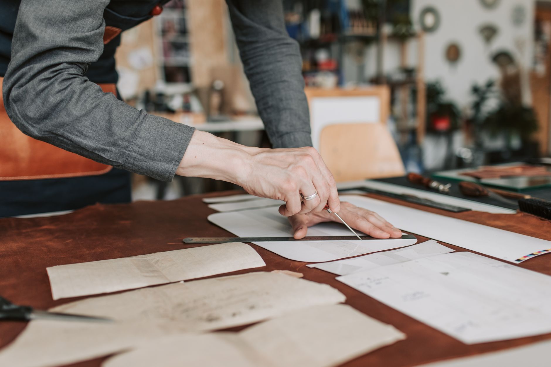 Artisan hands stitching a cylindrical leather strap on a workshop table