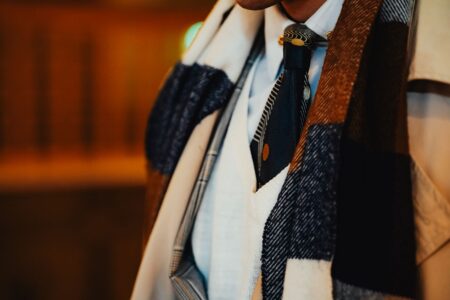 A neatly folded white stock tie laid flat, showing its structured horizontal shape and simple bar pin