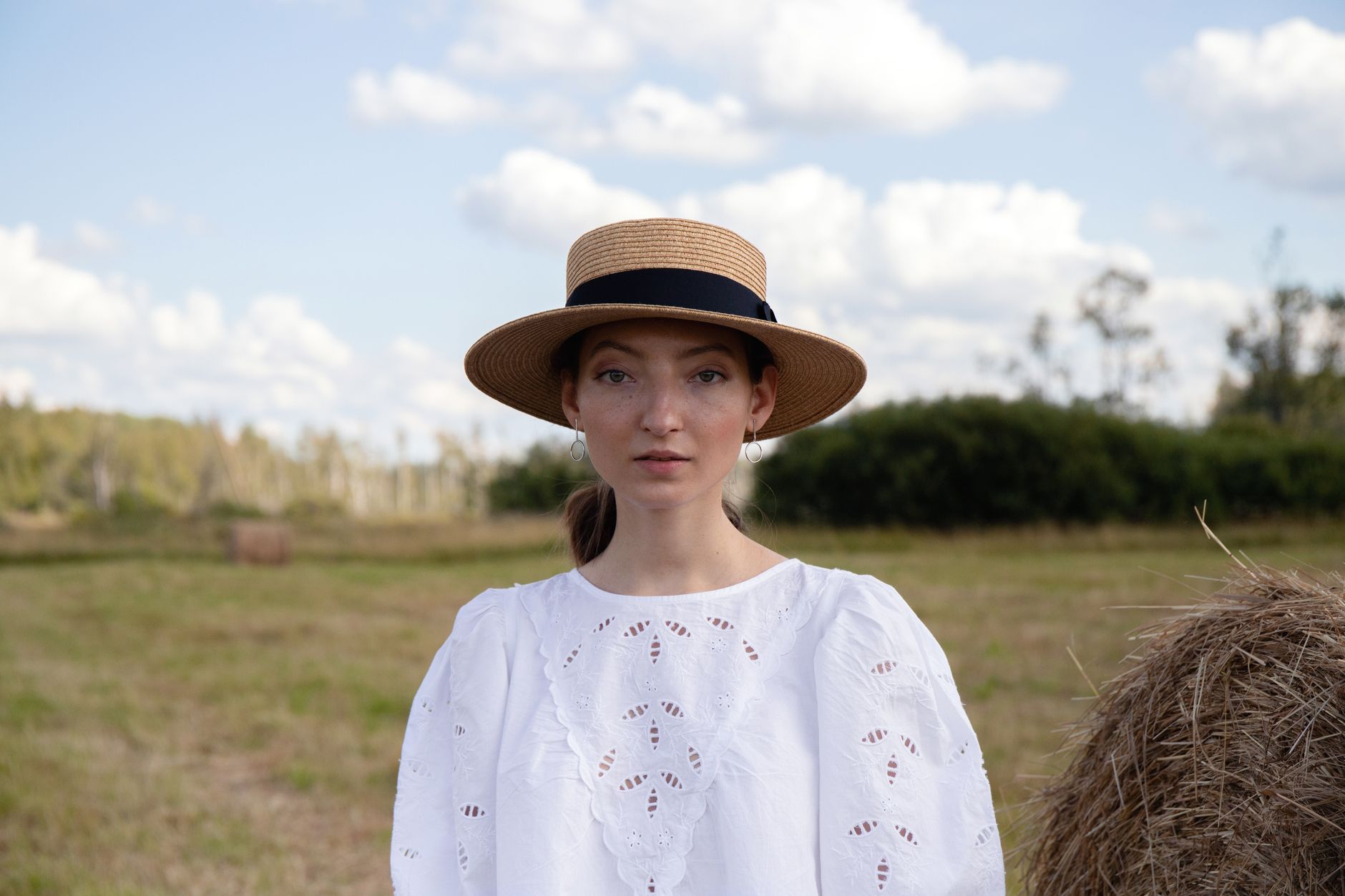 A classic flat-brimmed straw boater hat displayed against a light background