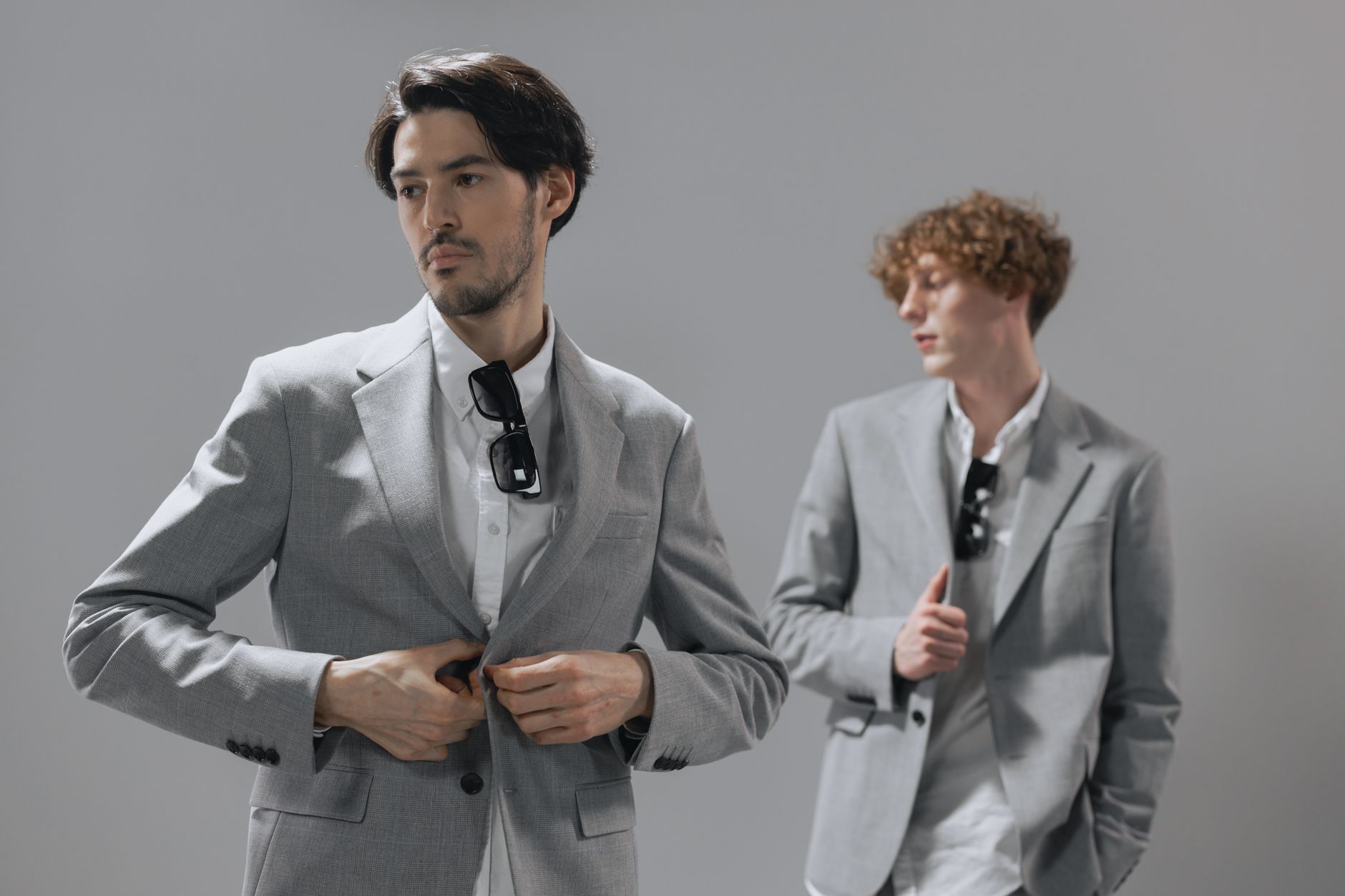A model in a wide-shoulder relaxed two-piece suit styled with an open collar and soft neckwear detail