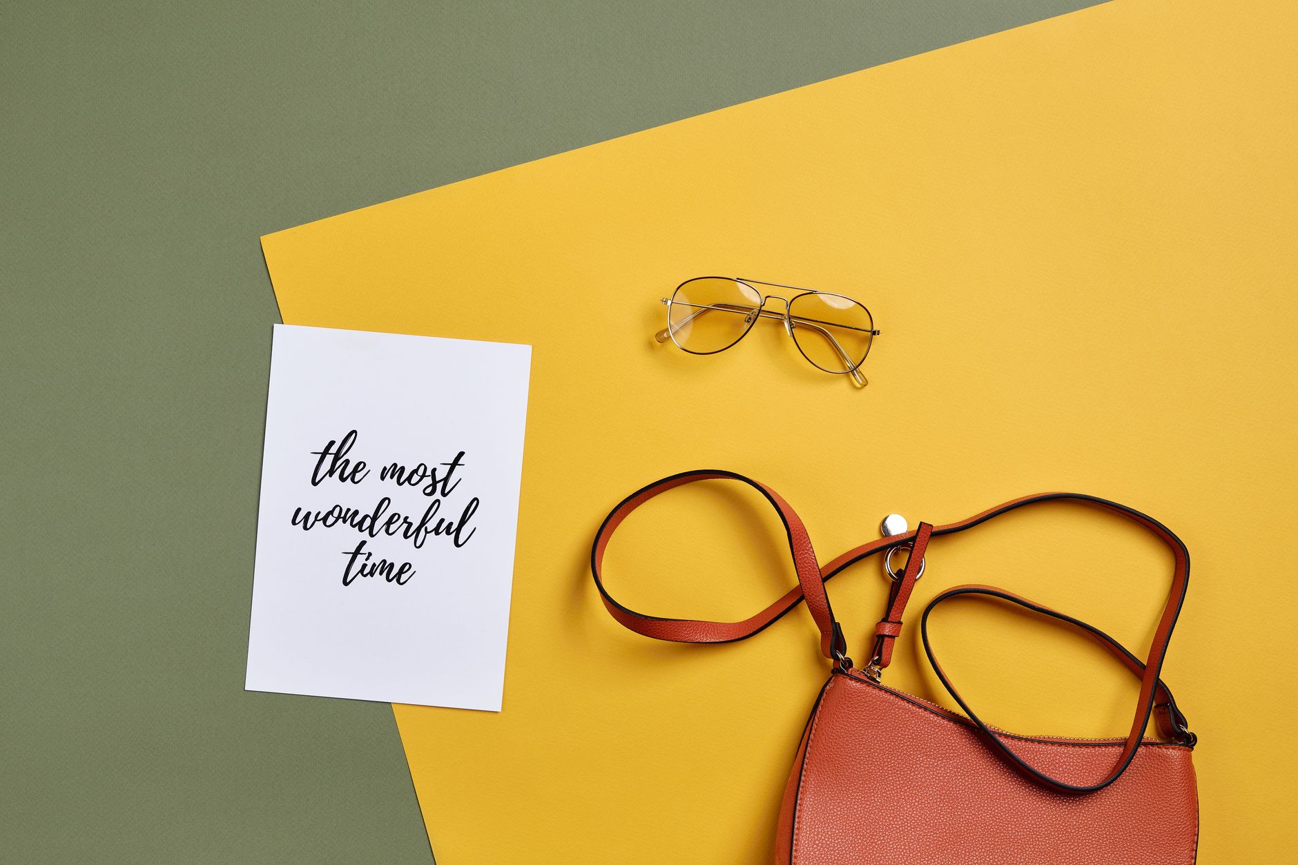 Flat lay of minimalist leather accessories including a slim belt on neutral background