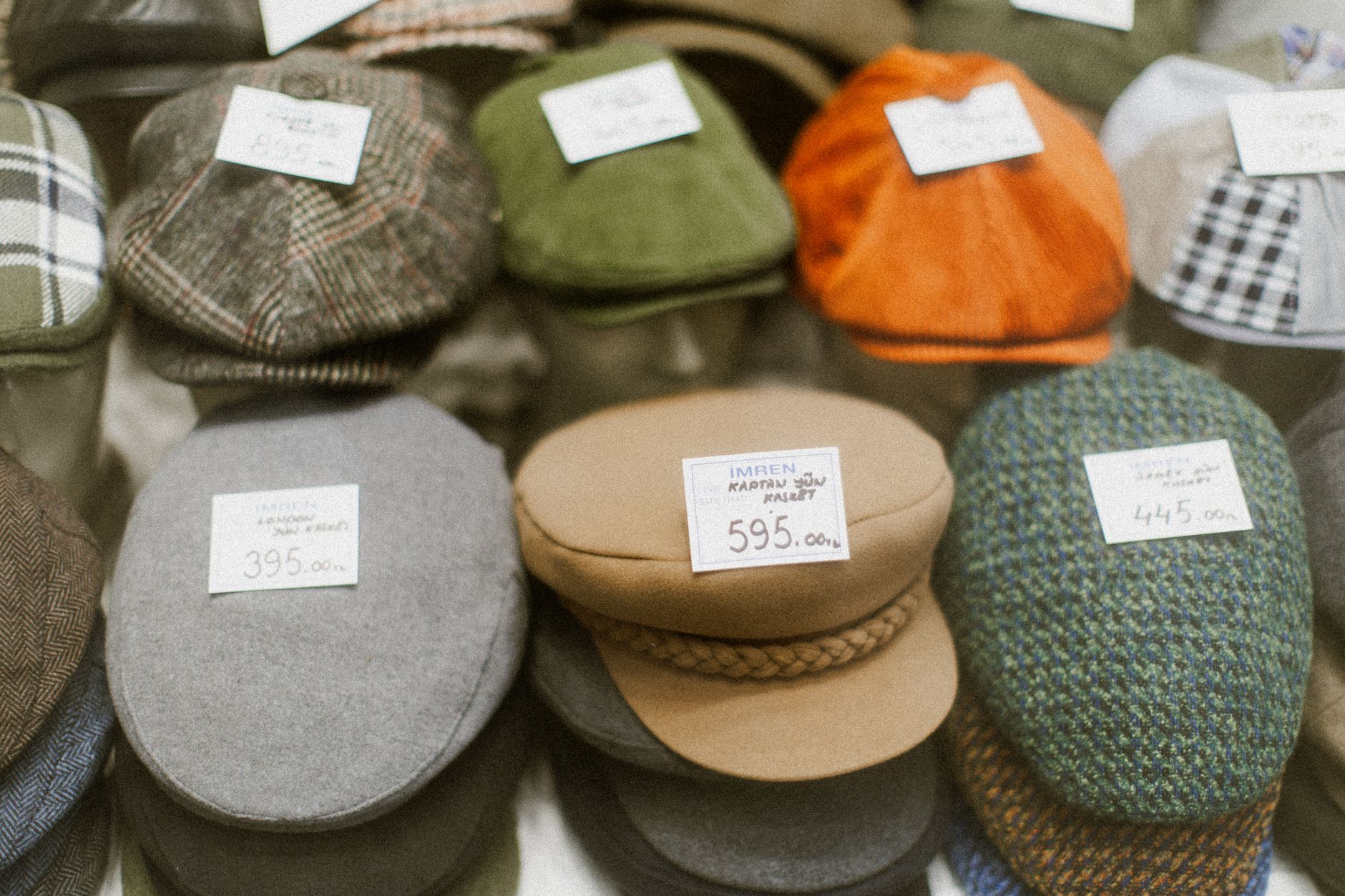 Row of structured flat caps displayed on a retail shelf showing varied dark colorways