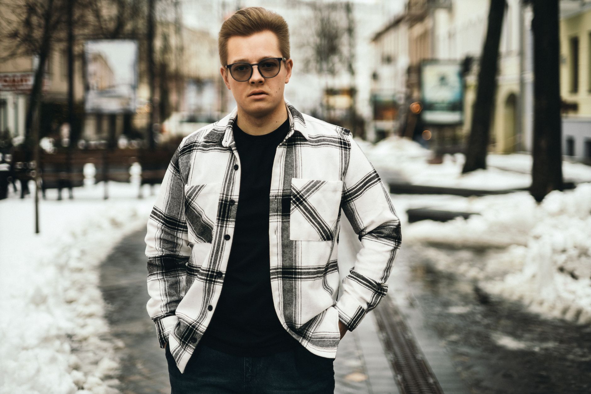 Person wearing long utilitarian outerwear layered over wide trousers on a city street