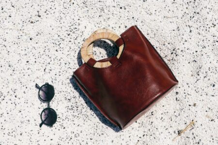 Close-up of a sculptural leather bag handle with ergonomic contours on a structured tote