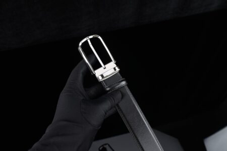 Close-up of leather strap with metal buckle hardware on a structured bag