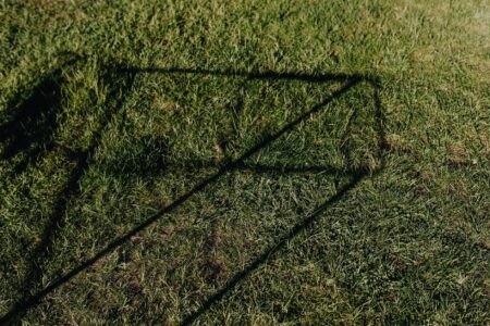 A croquet mallet resting on a grass lawn, showing the shaft and metal ferrule detail