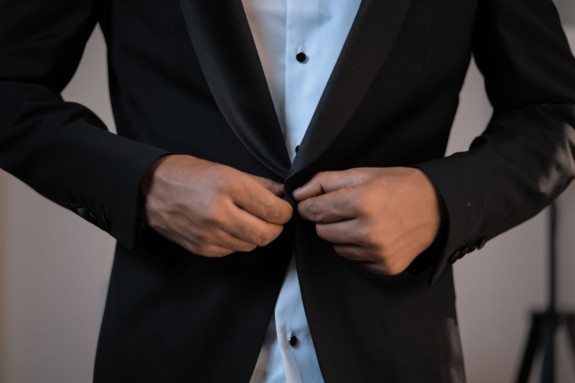 Close-up of the back of a structured tailored jacket showing a clean vent with a small anchor button at the base