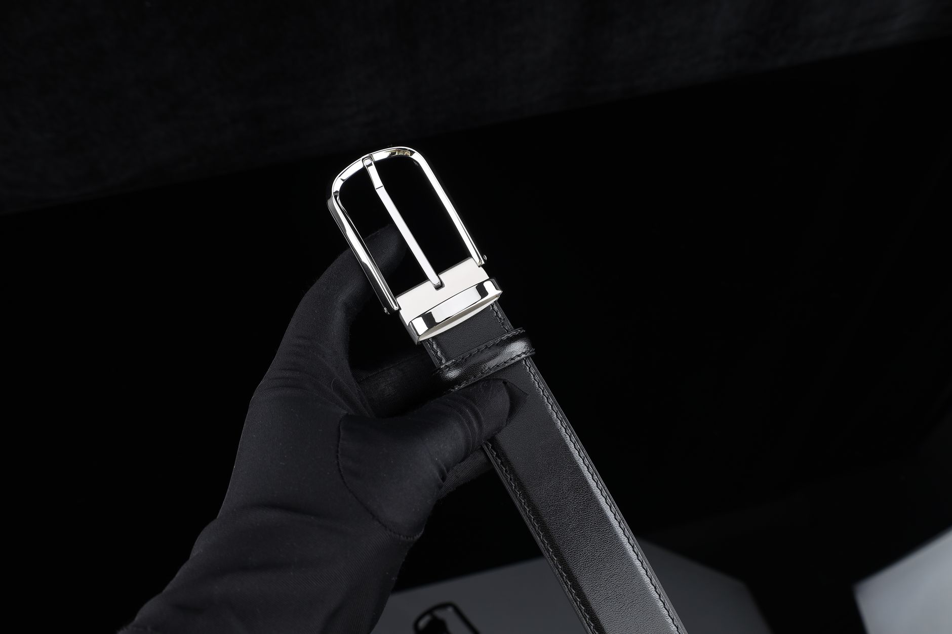 Close-up of flat metal buckle hardware on a thick leather belt strap