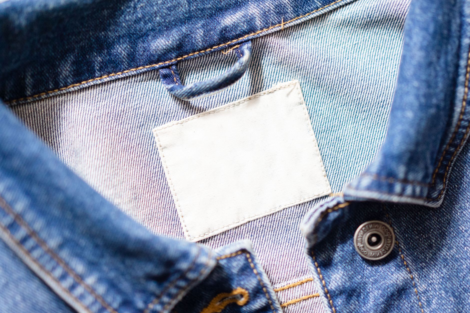 Detail shot of a tailored jacket front with tonal button and fabric loop fastening