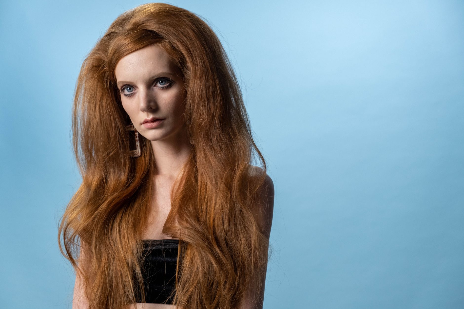 A model wearing a structured metal headband with slicked-back hair against a plain studio backdrop